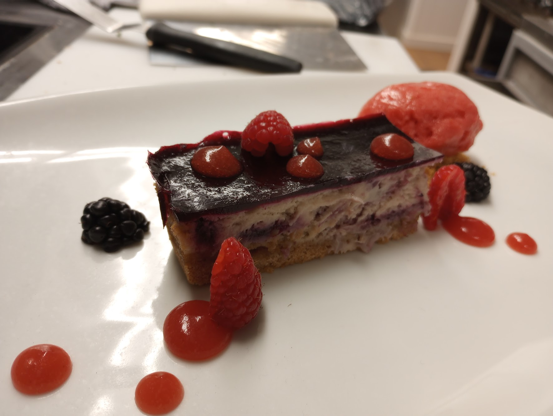 Berry dessert slice with raspberry coulis and sorbet